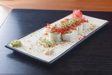 Maki Suşi California ruloları taze somon, salatalık ve krem peynirli Philadelphia kırmızı havyar ve bitkilerle birlikte.