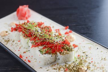 Maki Suşi California ruloları taze somon, salatalık ve krem peynirli Philadelphia kırmızı havyar ve bitkilerle birlikte.