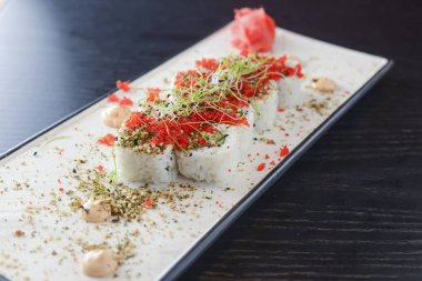 Maki Suşi California ruloları taze somon, salatalık ve krem peynirli Philadelphia kırmızı havyar ve bitkilerle birlikte.