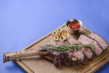 Domates soslu biftek, acı biber ve ahşap tahta tahtadaki baharatlar mavi bayram arka planında yatıyordu.