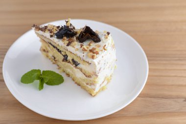 Beyaz bir tabakta servis edilen kuru erik, ceviz ve kremalı vanilyalı kek bisküvisi.