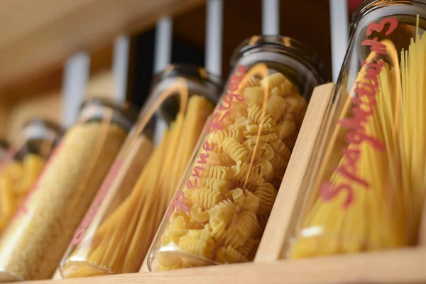 Different kinds of italian pasta collection set, raw pasta in jars on wooden shelf. Cannelloni, spaghetti, penne rigate. — 스톡 사진