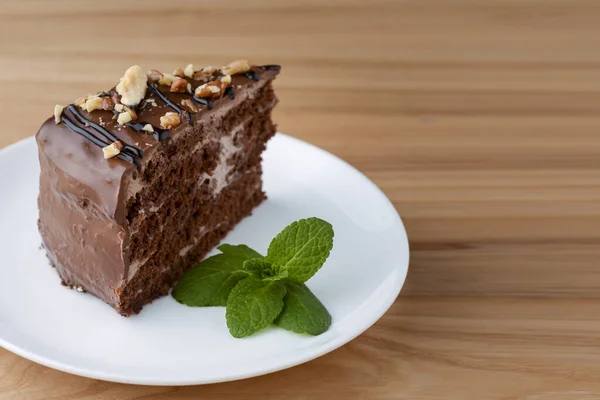 Słodka czekolada pająk web cake z lukrem na górze podawane na białym talerzu na jasnym drewnianym tle. — Zdjęcie stockowe