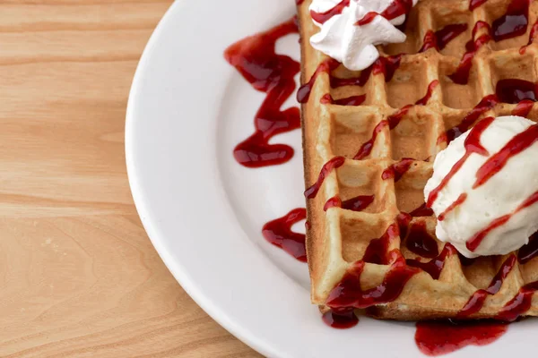 Plate of belgian waffles with ice cream and fruit strawberry caramel sauce on wooden table background — 스톡 사진