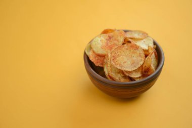 Patates cipsi, gevrek sağlıksız cips, abur cubur, fast food konsepti. Parlak sarı arka planda bir kasede patates cipsi..