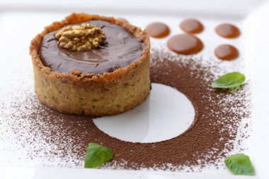 Çikolata kremalı brüle kakao tozu, ceviz ve nane yaprağı. Geleneksel Fransız vanilyalı tatlı.