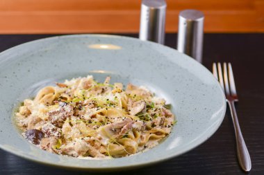 Beyaz tabakta servis edilen geleneksel İtalyan makarnası, kirazlı domates, parmezan peyniri ve maydanoz.