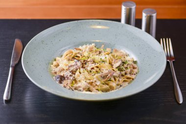 Beyaz tabakta servis edilen geleneksel İtalyan makarnası, kirazlı domates, parmezan peyniri ve maydanoz.