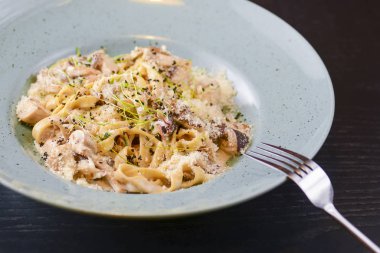 Beyaz tabakta servis edilen geleneksel İtalyan makarnası, kirazlı domates, parmezan peyniri ve maydanoz.