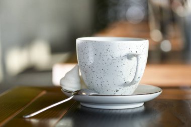 Siyah çaylı çay fincanı küçük bir tabakta, beyaz çaydanlık da siyah ahşap masada.