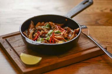 Tavada domuz kulağı atıştırması. Baharatlı et ızgara domuz rustik ahşap kesme tahtasında kızartma tavasında servis edilir..