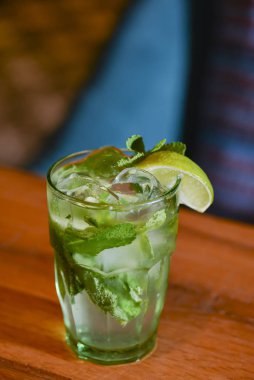 Barda masanın üzerinde klasik taze mojito. Buzlu, naneli ve limonlu alkol kokteyli. Arka planı bulanık..