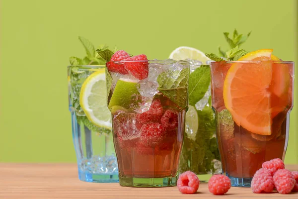 Quatro bebidas tropicais mistas, coquetéis de laranja, limão e framboesas sobre fundo verde pastel brilhante . — Fotografia de Stock