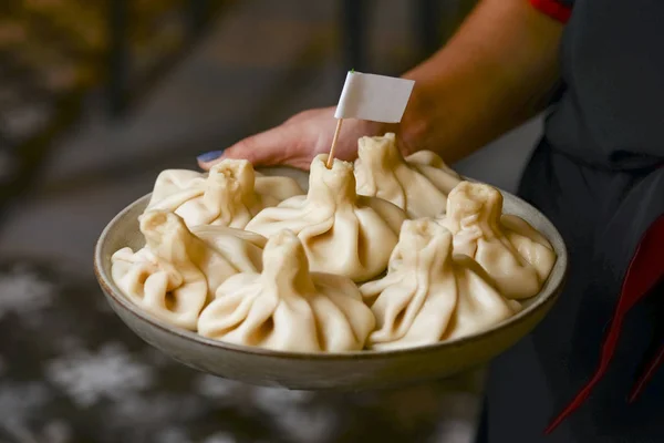 Waiter holds a plate of tasty food. Georgian dumplings Khinkali with meat. Traditional georgian cuisine and food. — Stock Photo, Image