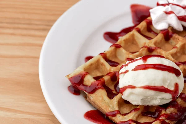 Plate of belgian waffles with ice cream and fruit strawberry caramel sauce on wooden table background — 스톡 사진