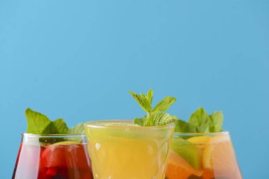 Limonlu, limonlu ve kırsal masada farklı bardaklarda servis edilen üç tropikal karışık içecek..