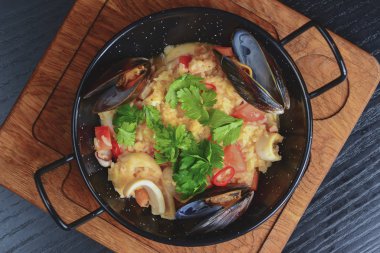 İçinde deniz mahsulleri olan kuskus. Lokantada servis edilen üç istiridye, ahşap kesme tahtasının üzerinde, kırsal karanlık masada..