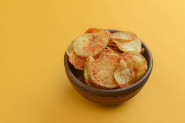 Patates cipsi, gevrek sağlıksız cips, abur cubur, fast food konsepti. Parlak sarı arka planda bir kasede patates cipsi..