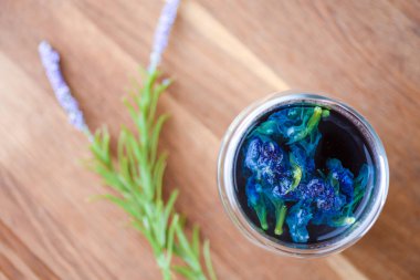 Bir fincan kelebeğin üst görüntüsü bezelye mavisi bezelye çiçeği, sağlığın için mavi bezelye açık ahşap masada içmek..