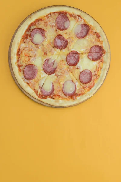 Плоский шар піци пепероні ізольований на яскраво-жовтому тлі. Піца салямі нарізати скибочками. Концепція фаст-фуду, нездорової їжі . — стокове фото