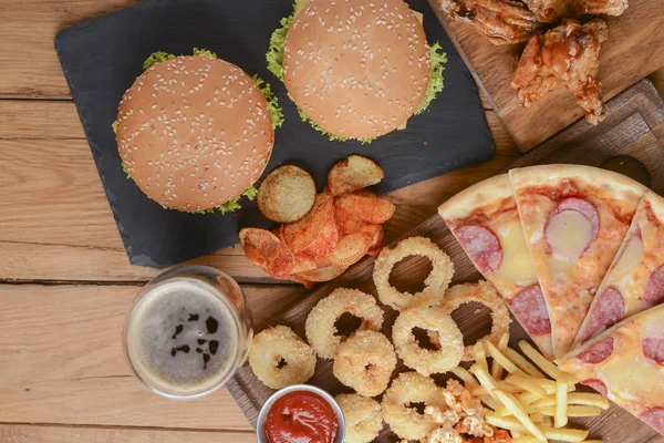 Koncepcja Fast food z tłustej smażonej cebuli, hamburgery i pizza z frytkami i popcornem. Koncepcja żywności niezdrowej. — Zdjęcie stockowe