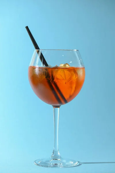 Egy pohár gyümölcs likőr borospohárban egy darab citrom és fekete műanyag szalma izolált pasztell kék háttér. — Stock Fotó