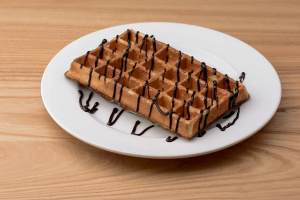 Prato de waffles belgas com molho de caramelo de chocolate no fundo da mesa de madeira. Cozinha tradicional belga, sobremesa — Fotografia de Stock
