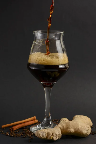 Un vaso alto de cerveza fría artesanal oscura con especias sobre fondo negro. Lúpulo, anís, canela, jengibre. Copiar espacio —  Fotos de Stock