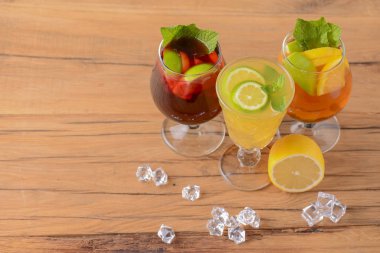 Limonlu, limonlu ve kırsal masada farklı bardaklarda servis edilen üç tropikal karışık içecek..