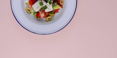 Beyaz tabakta servis edilen beyaz peynirli ve sebzeli geleneksel Yunan salatası..