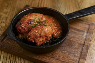 Stuffed cabbage leaves with minced meat and rice in tomato sauce on in a pan on wooden table. Lazy cabbage rolls.