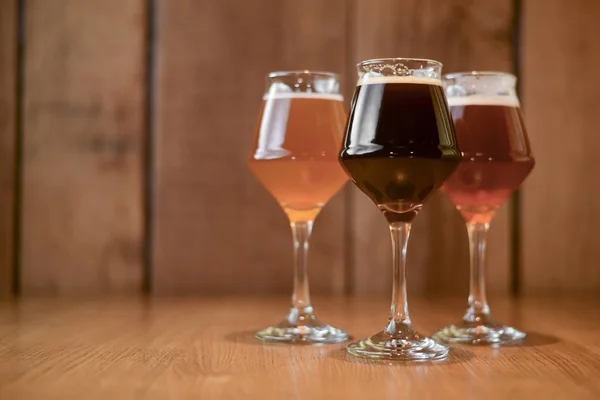 Drei Gläser mit verschiedenen Bieren auf einem Holztisch in einer Bar. Food-Fotografie-Konzept mit Kopierraum — Stockfoto