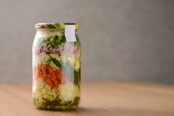 Salade russe saine maison Olivier avec légumes, viande et mayonnaise dans un pot en verre sur fond de table en bois — Photo