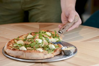 Lokantada hafif ahşap bir masada servis edilen lezzetli İtalyan büyük pizzası. Restoran yemek fotoğrafçılığı.