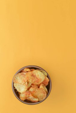Patates cipsi, gevrek sağlıksız cips, abur cubur, fast food konsepti. Parlak sarı arka planda bir kasede patates cipsi..