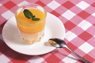 Mango panna cotta, mango jöle ve nane şekeri ile kırmızı ekose masa örtüsünde servis edilir..