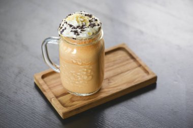 Dondurma, krema ve çikolatalı buzlu kahve. Bir bardak soğuk, şekerli, bulanık arka planı olan kahve..