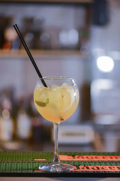 Deliciosa bebida de cóctel en la mesa del bar. Bebida de alcohol amarillo con una paja de plástico en un vaso . — Foto de Stock