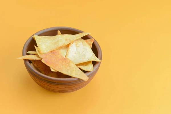 Nacho cheese tortilla chips in a bowl. Crisp golden unhealthy chips, junk food, fast food concept.