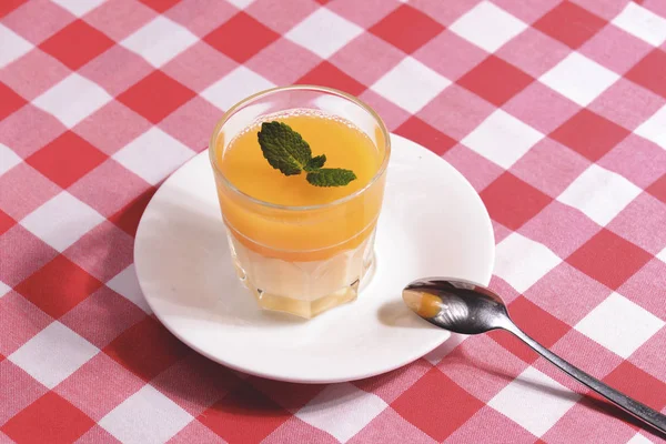 Mango Panna cotta s mangovým želé a mátou podávané ve skleněném obroučkovém ubrusu. — Stock fotografie