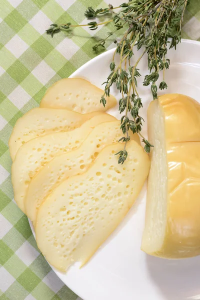 Assortiment de fromage servi sur une assiette blanche. Morceaux de fromage aux herbes sur fond de carreaux verts . — Photo