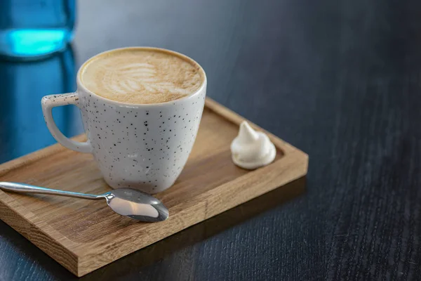 Egy csésze kávé a kis táblán fekete háttér felett. Latte művészet. Kis kávésbögre és kanál. — Stock Fotó