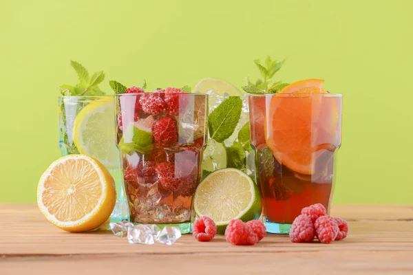 Cztery tropikalne mieszane napoje, koktajle pomarańczowe, cytrynowe i malinowe na jasnym pastelowym zielonym tle. — Zdjęcie stockowe