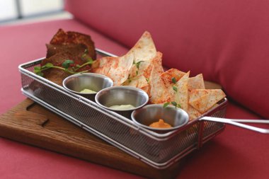 Nachos tortilla cipsi ve tepside farklı çeşitte sos..