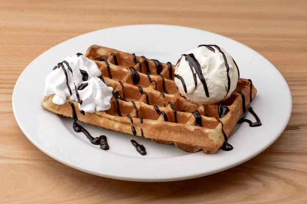Plate of belgian waffles dessert with ice cream and chocolate caramel sauce on wooden table background. — Stock Photo, Image