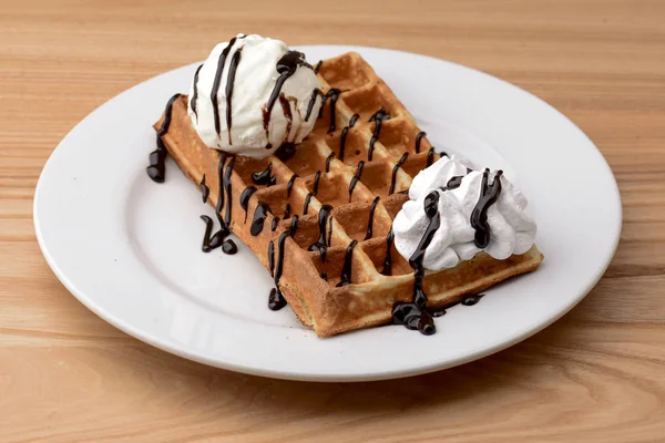 Plate of belgian waffles dessert with ice cream and chocolate caramel sauce on wooden table background. — 스톡 사진