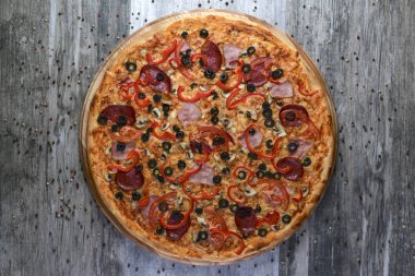 Lezzetli İtalyan pizzasının kır ağacında çekilmiş düz bir fotoğrafı. Pepperoni, peynir ve biber. Lezzetli yemek..