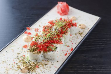 Maki Suşi California ruloları taze somon, salatalık ve krem peynirli Philadelphia kırmızı havyar ve bitkilerle birlikte.