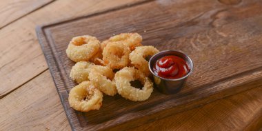 Ekmek kırıntıları ve kızartılmış altın çıtır soğan halkaları. Fast food, abur cubur kavramı.