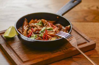 Tavada domuz kulağı atıştırması. Baharatlı et ızgara domuz rustik ahşap kesme tahtasında kızartma tavasında servis edilir..